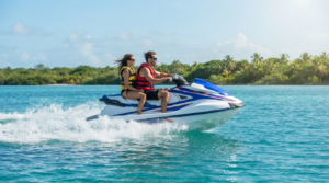 Two riders in life jackets on a rented jet ski speeding across turquoise water near Siesta Key