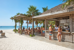 Beach pavilion with shaded seating and a snack counter beside the sand